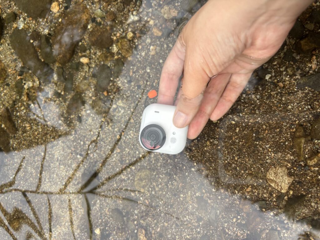 Insta360 GO Ultraのカメラ本体を手で川に沈める様子